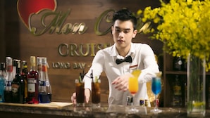 A bartender at a bar with a wooden backdrop and a sign that reads "Miss Cruise." - Mon Chéri Cruises (Tuan Chau)
