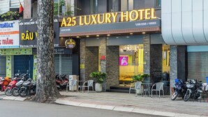 A25 Luxury Hotel with a modern facade, outdoor seating area, and multiple motorcycles parked outside. - A25 Premium Hotel - 142 Bui Thi Xuan (Ho Chi Minh City)