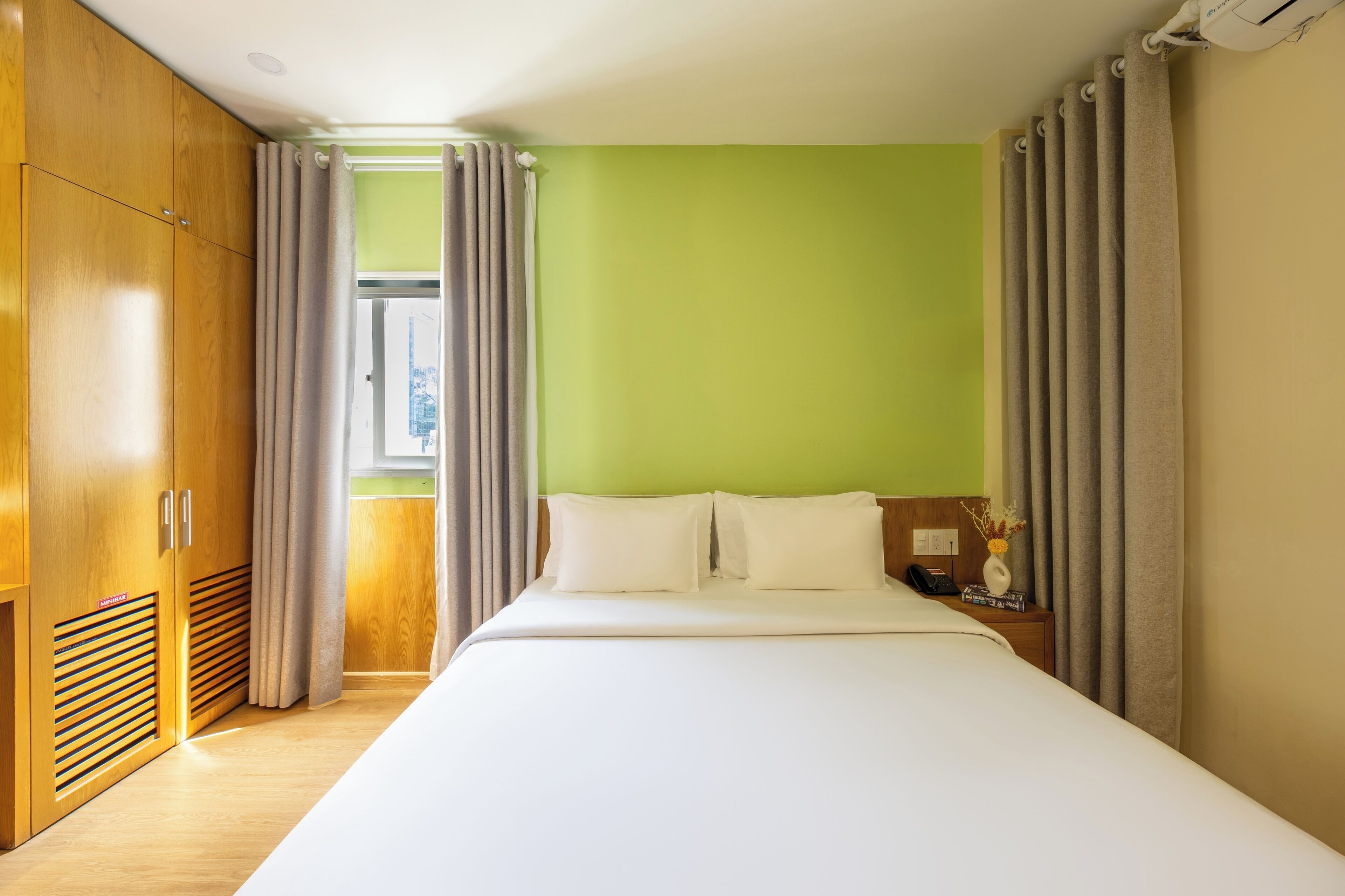 Une chambre d’hôtel avec un grand lit, une armoire en bois et une fenêtre avec des rideaux.