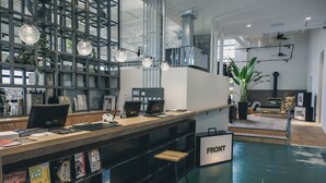 A modern reception area with a wooden counter, multiple computer stations, and a large plant.