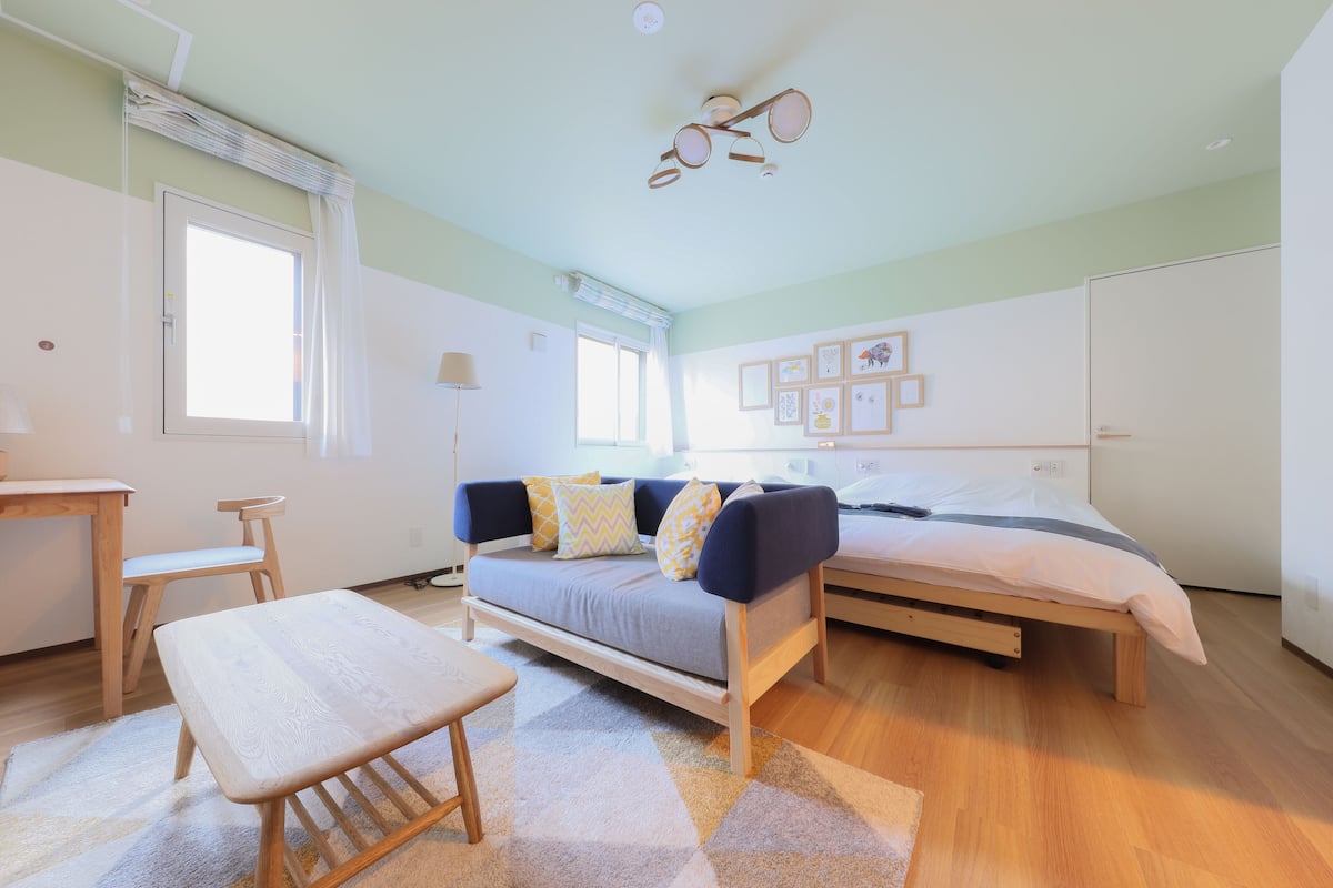A modern bedroom with a bed, a sofa, a desk, and a chair.