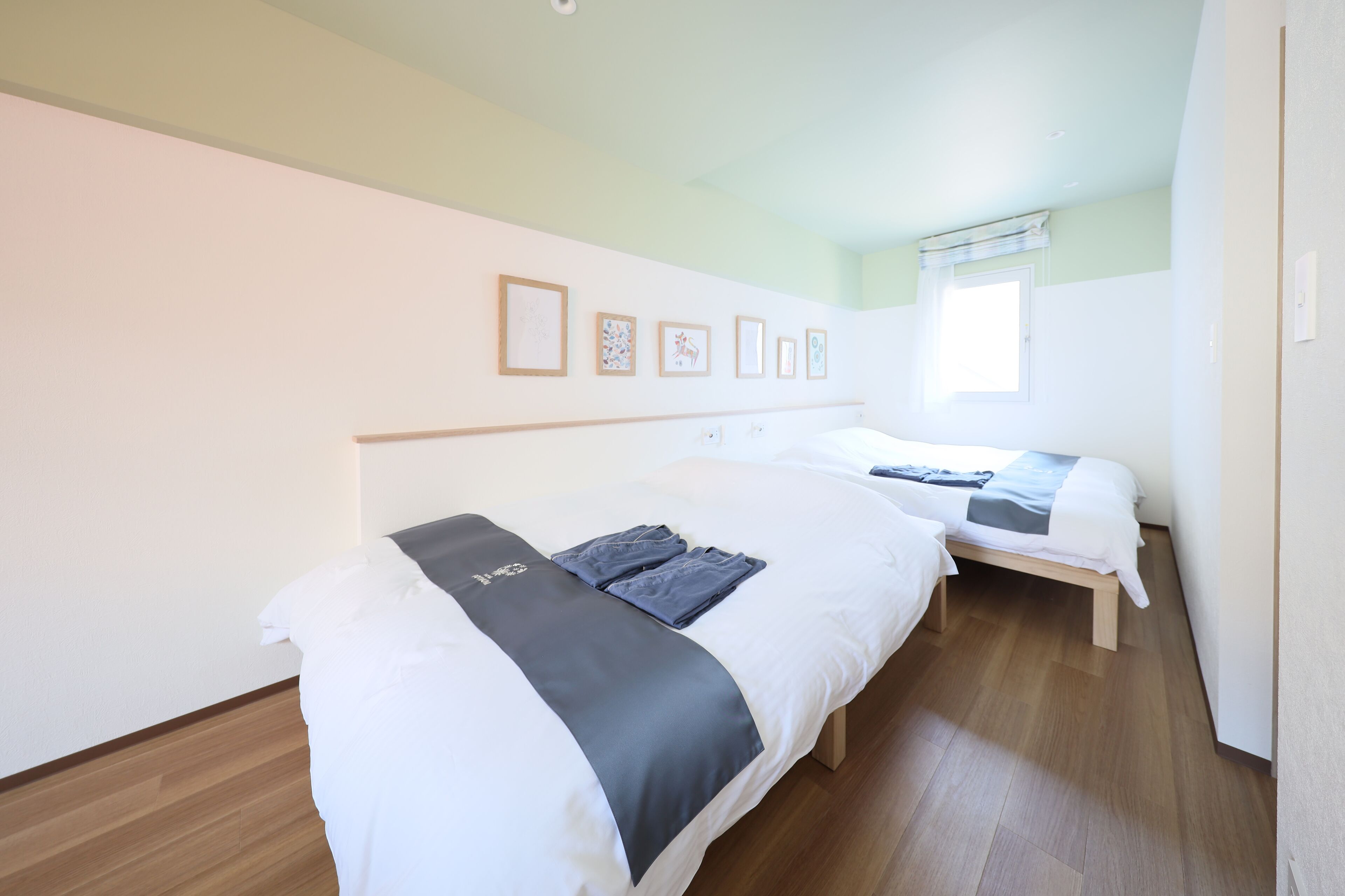 Una habitación de hotel con dos camas, piso de madera y cuadros en la pared.