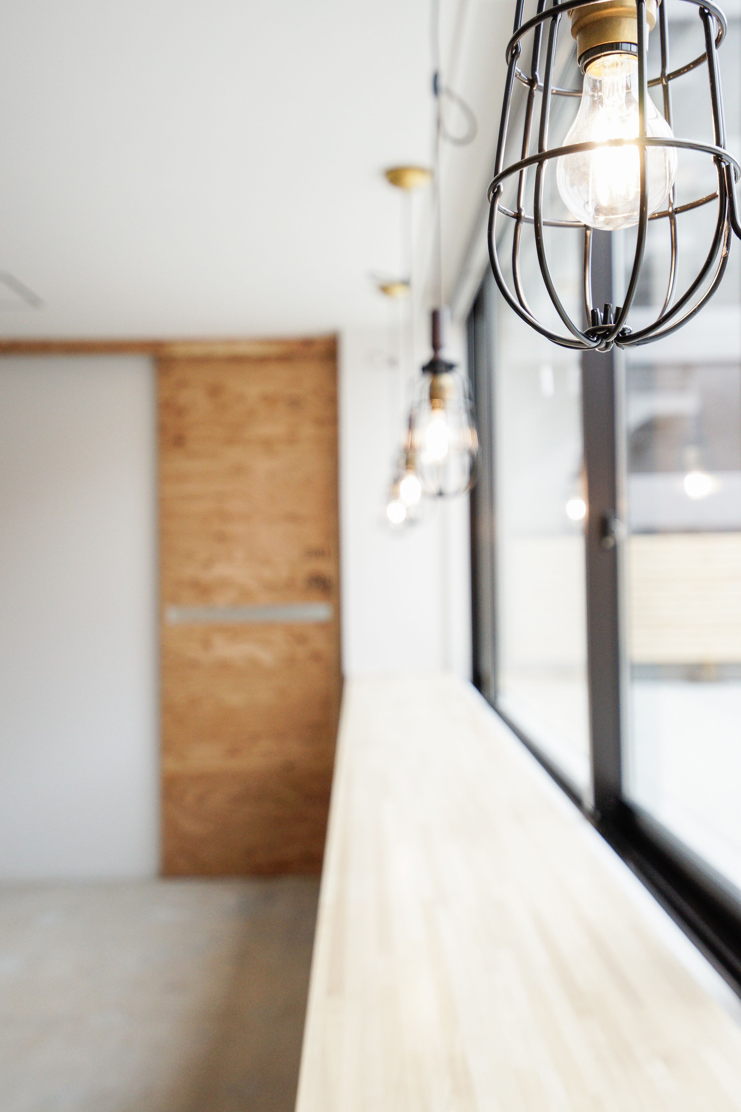 Un interior moderno con un banco de madera, lámparas de metal y un ventanal grande.