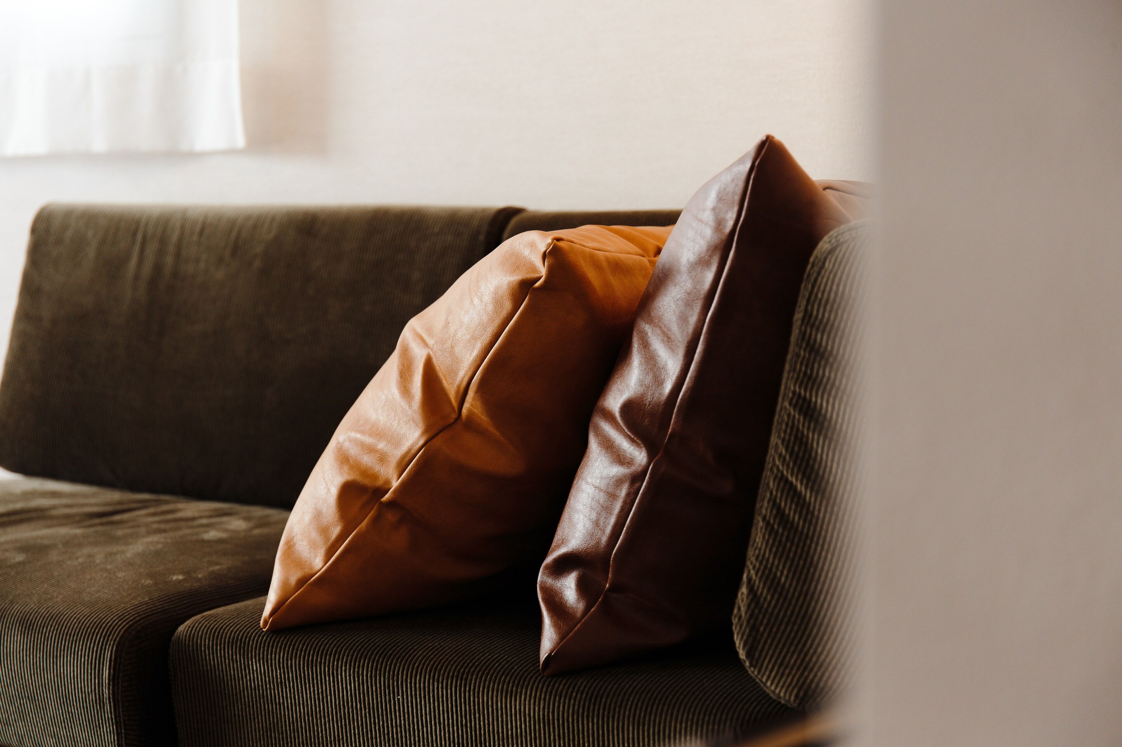 A brown leather sofa with two cushions.