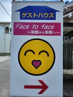 Una señal direccional con un símbolo de corazón y la frase 'Face to face' en varios idiomas.