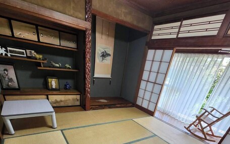 A tatami mat room with a low table, a wooden bench, and a sliding door with a view.