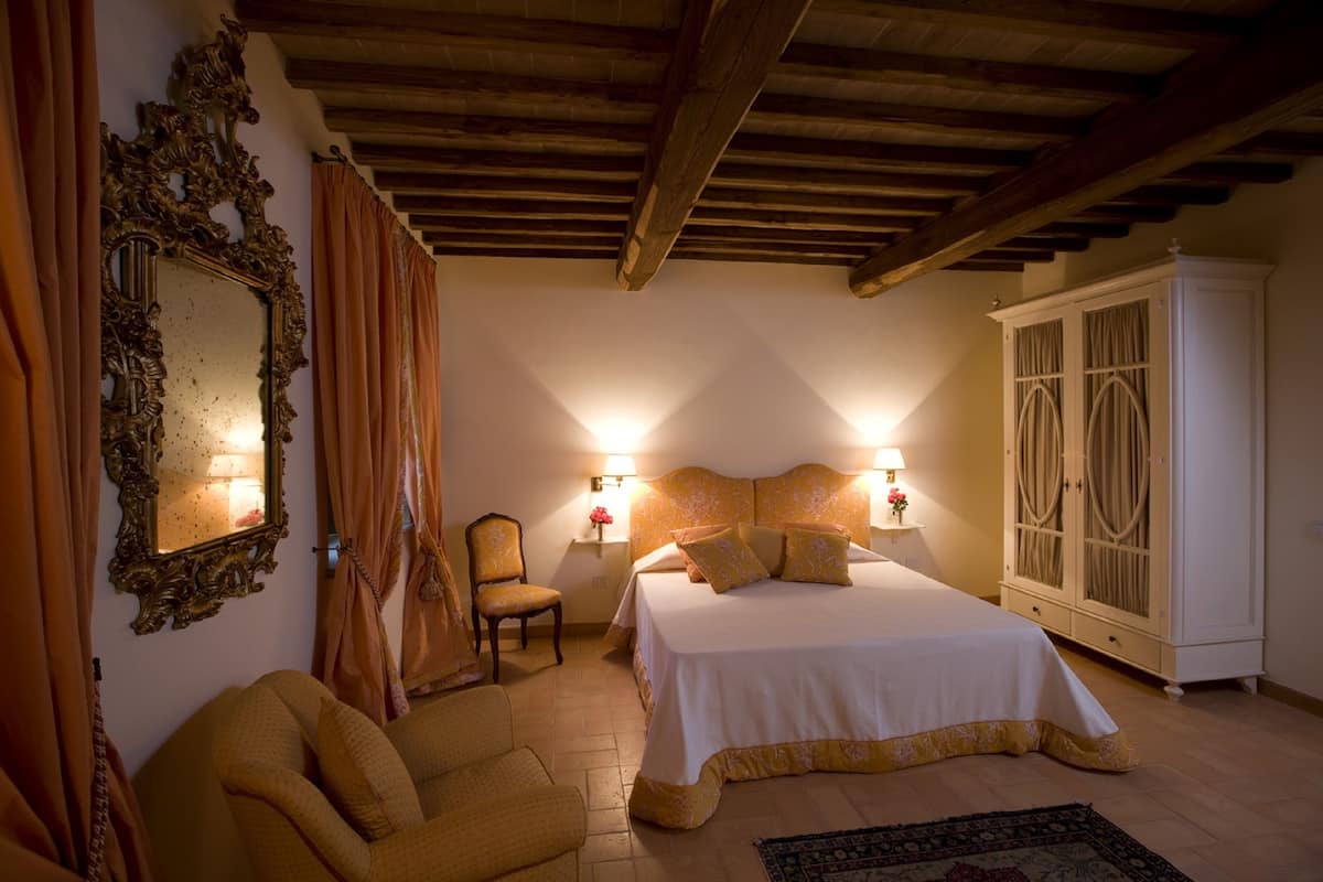 Een slaapkamer met een bed, een stoel, een kledingkast en een spiegel.