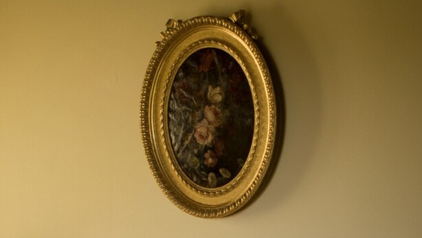 Un canapé avec des coussins à motifs et une œuvre d’art encadrée accrochée au mur.