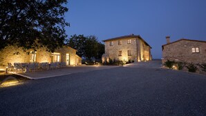 A stone building with a paved driveway and outdoor seating area. - Villa Il Castagno Wine & Resort (Siena)
