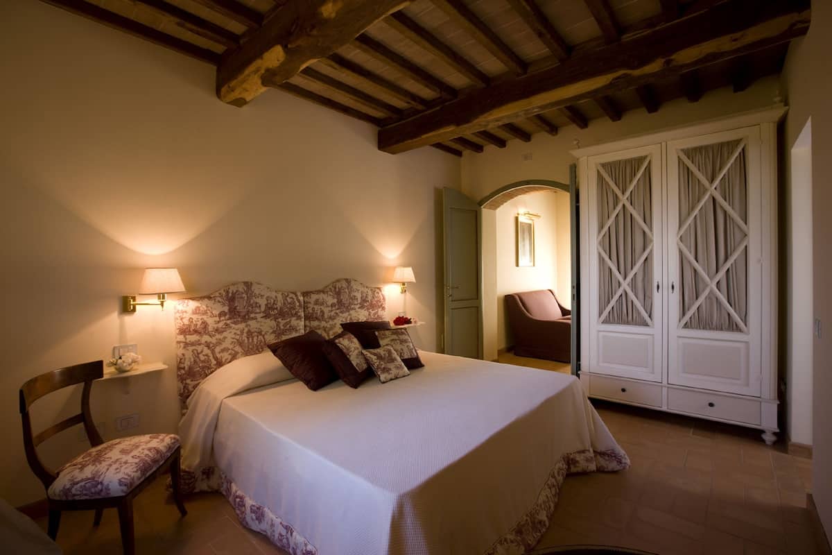 Een slaapkamer met een bed, twee bedlampen, een stoel en een kledingkast.
