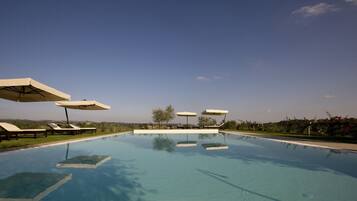 Alberca al aire libre, sombrillas en la alberca y camastros