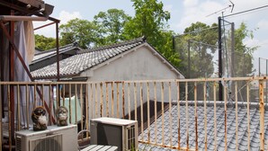 A balcony with a wooden bench, potted plants, and a small building with a tiled roof. - Kyoto Tenseian (Kyoto)