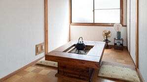 A traditional Japanese room with tatami flooring, a wooden ceiling, a large window, and a low table with a kettle. - Kyoto Tenseian (Kyoto)
