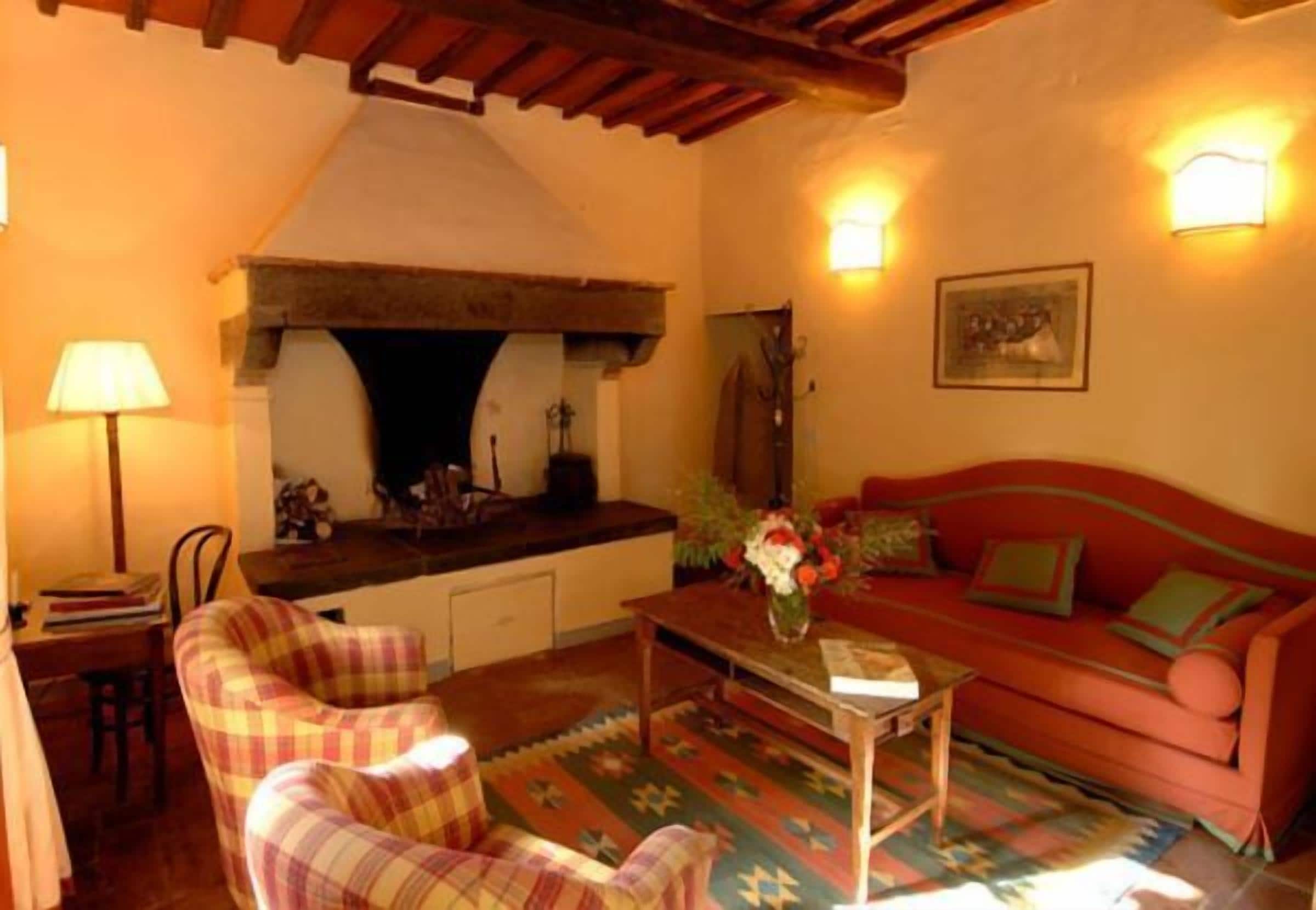 Una sala de estar acogedora con chimenea, sillones a cuadros, un sofá rojo y una alfombra estampada.