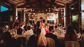A wedding reception in a rustic venue with wooden beams and stone walls.