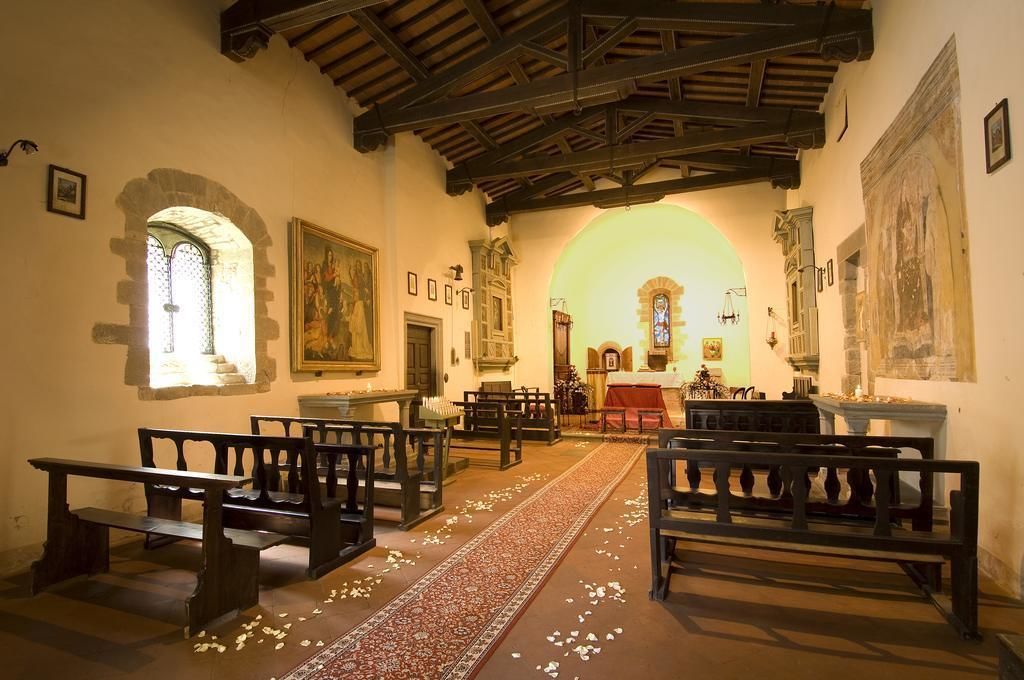 A church interior with wooden pews, a central aisle, and a stained glass window.