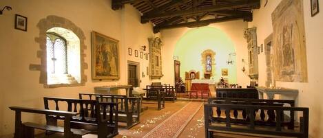 Interior de iglesia con bancos de madera, un pasillo central y un vitral.