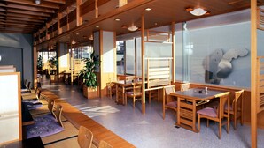 Un espace intérieur spacieux, doté de tables et de chaises en bois, de grandes fenêtres et d’un design moderne au niveau du plafond.