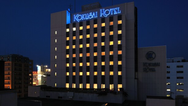 Un hôtel moderne, avec une enseigne lumineuse indiquant « Kokusaï Hotel ».
