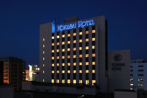 Un hôtel moderne, avec une enseigne lumineuse indiquant « Kokusaï Hotel ».