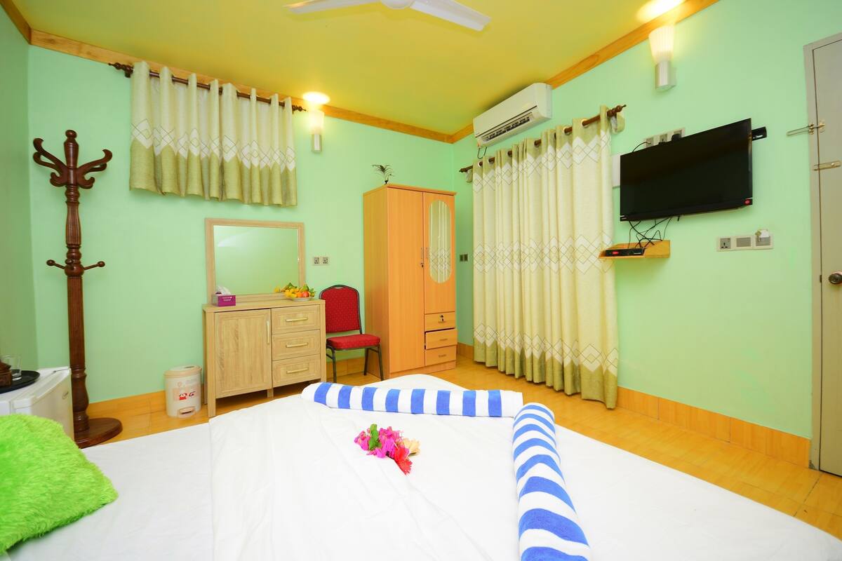 A hotel room with a bed, a wardrobe, a television, and a ceiling fan.