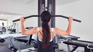 Un gimnasio con equipo de ejercicio, incluyendo una barra de dominadas, y una persona realizando una dominada.