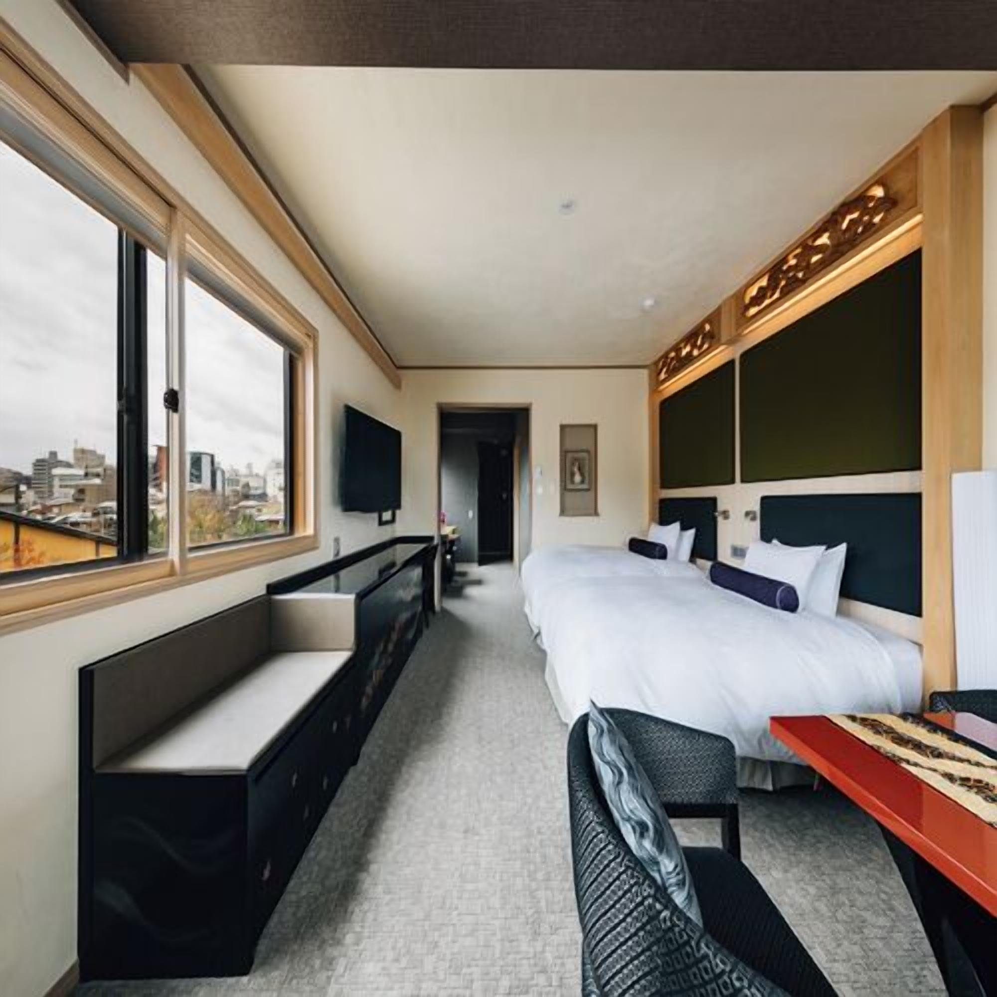 A hotel room with a large bed, a desk, a bench, and a TV.