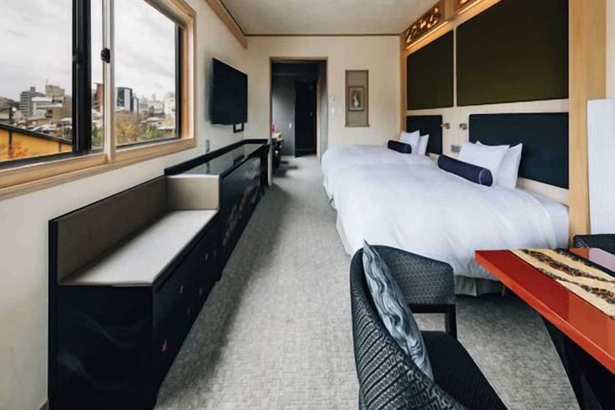 A hotel room with a large bed, a desk, a bench, and a TV.
