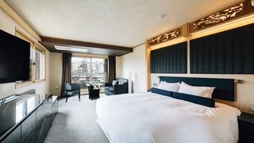 A hotel room with a large bed, a flat-screen TV, a desk, and a chair.