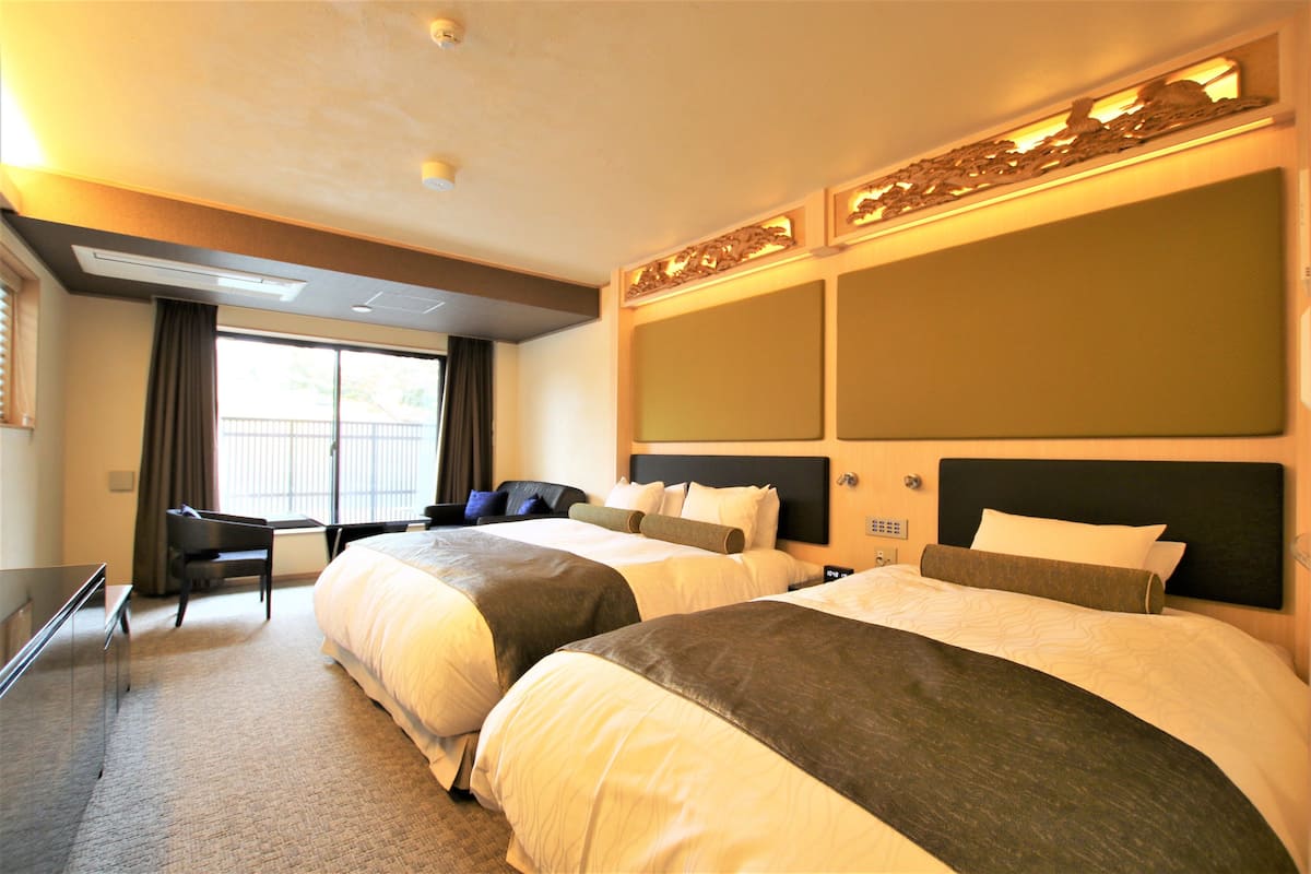 A hotel room with two beds, a desk, and a chair.