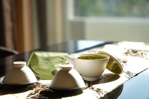 A table with a teapot, a cup of tea, and a green tea bag. - Hotel ALZA KYOTO (Kyoto)