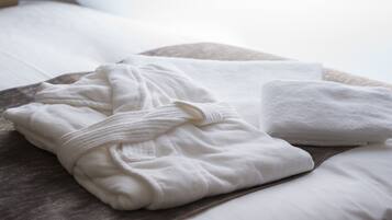 A neatly made bed with white linens and a folded bathrobe.