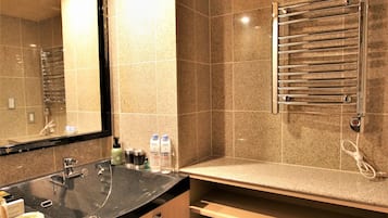 A modern bathroom with a black sink, a large mirror, a towel rack, and a shower area.