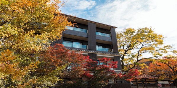 A multi-story building with a modern architectural style, featuring a balcony on the second floor and a covered outdoor seating area. - Hotel ALZA KYOTO (Kyoto)