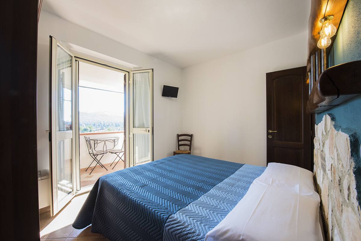 Ein Schlafzimmer mit Bett, Stuhl, Fernseher und einer Tür.