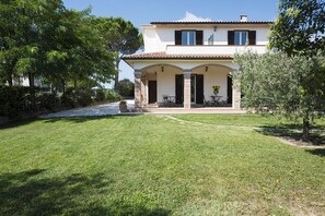 A two-story house with a covered patio and a well-maintained lawn.