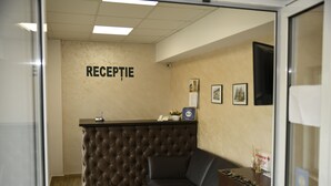 Un espace d’accueil doté d’un comptoir en cuir capitonné, d’un canapé en cuir noir et de tableaux encadrés accrochés au mur.