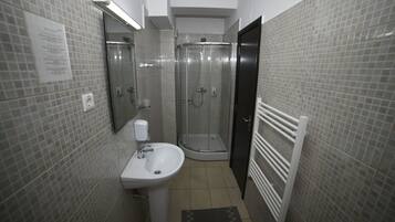 Un baño con cabina de ducha de vidrio, un lavamanos y un perchero para toallas.