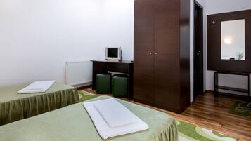 A room with two beds, a wardrobe, a desk with a computer, and a mirror.