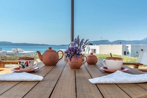 A wooden table with a view of the sea, a vase with lavender, and two teapots labeled "Country Creamer" and "Sugar." - The Millers House Adamas Sea View (Milos)