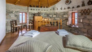 Una stanza rustica con parete in pietra, arredi in legno, un letto con trapunte e soffitto in legno.