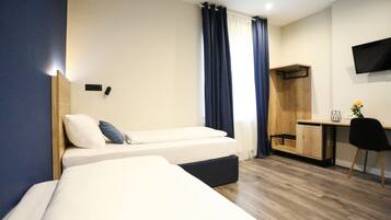 Ein Hotelzimmer mit zwei Betten, einem Schreibtisch, einem Stuhl, einem Fernseher und einem Kleiderschrank.