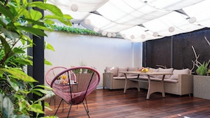 Un patio con mobiliario de mimbre, una mesa con fruta y una planta colgante.