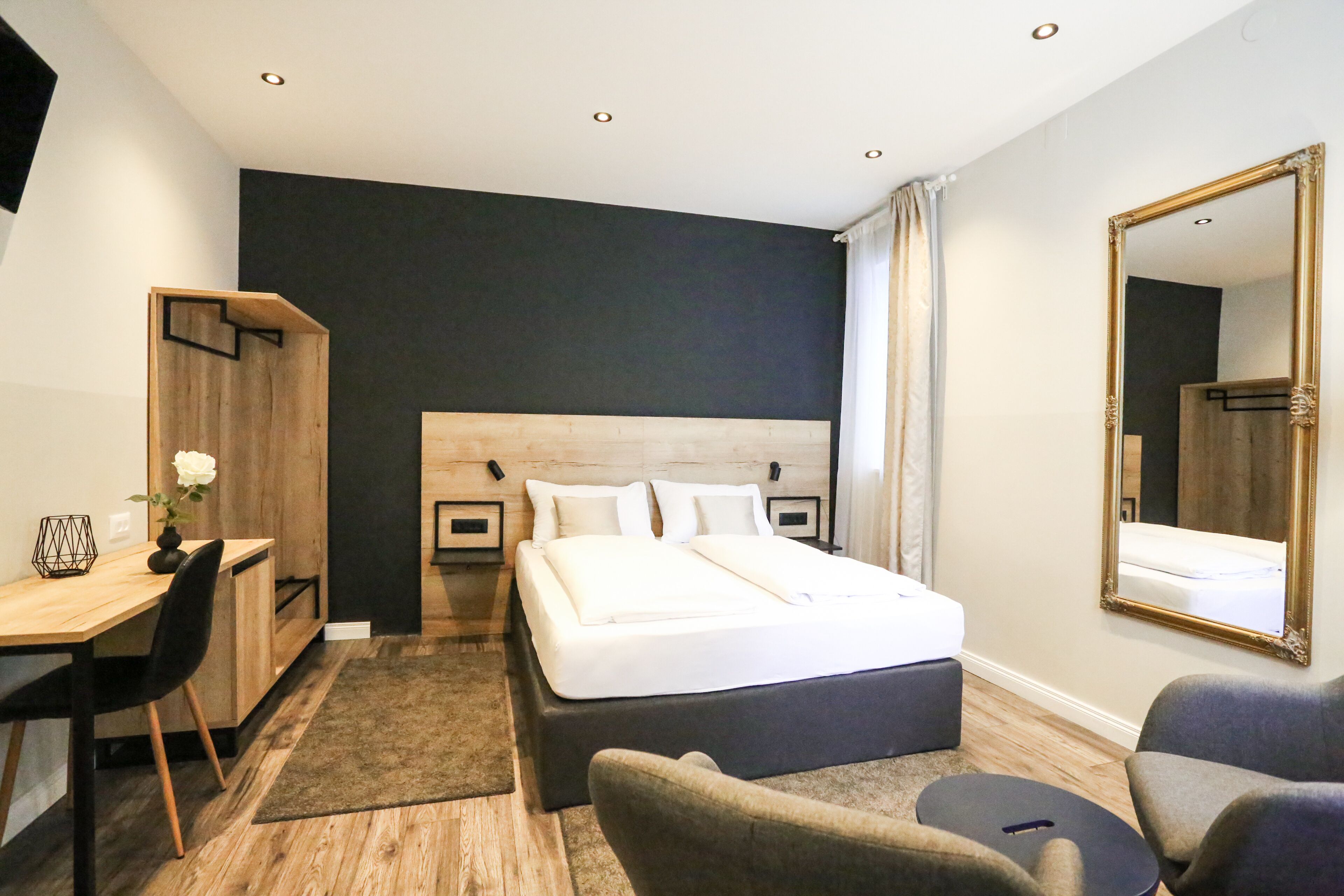 Una habitación de hotel moderna con una cama grande, un escritorio, una silla y un espejo.