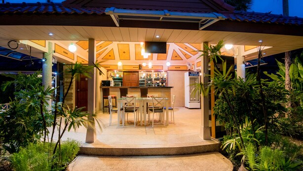 An outdoor dining area with a bar, surrounded by tropical plants.