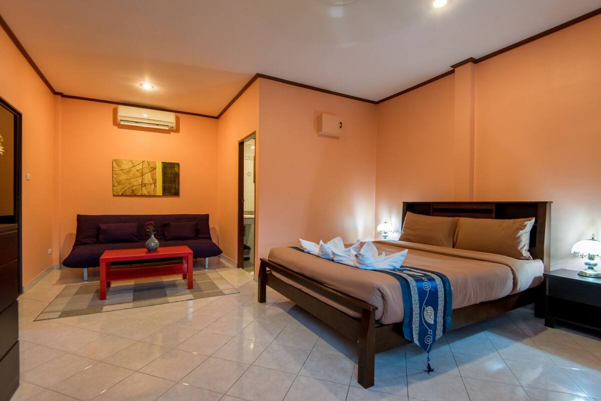 Una habitación de hotel con una cama, un sofá, una mesita y una mesita de noche.