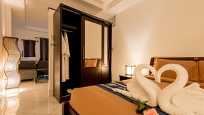 A hotel room with a bed, a sitting area with a sofa, and a bathroom with a mirror and towel rack.