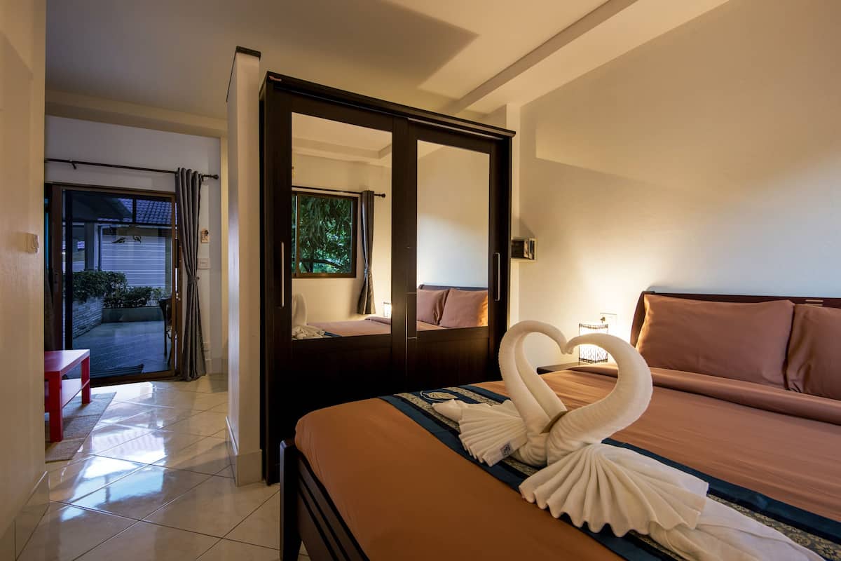 Habitación de hotel con cama, un espejo grande y vistas al exterior.