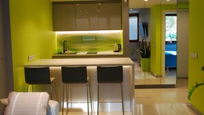 A modern kitchen with a bar area, green walls, and a large mirror. - Good Time Apartments (Warsaw)