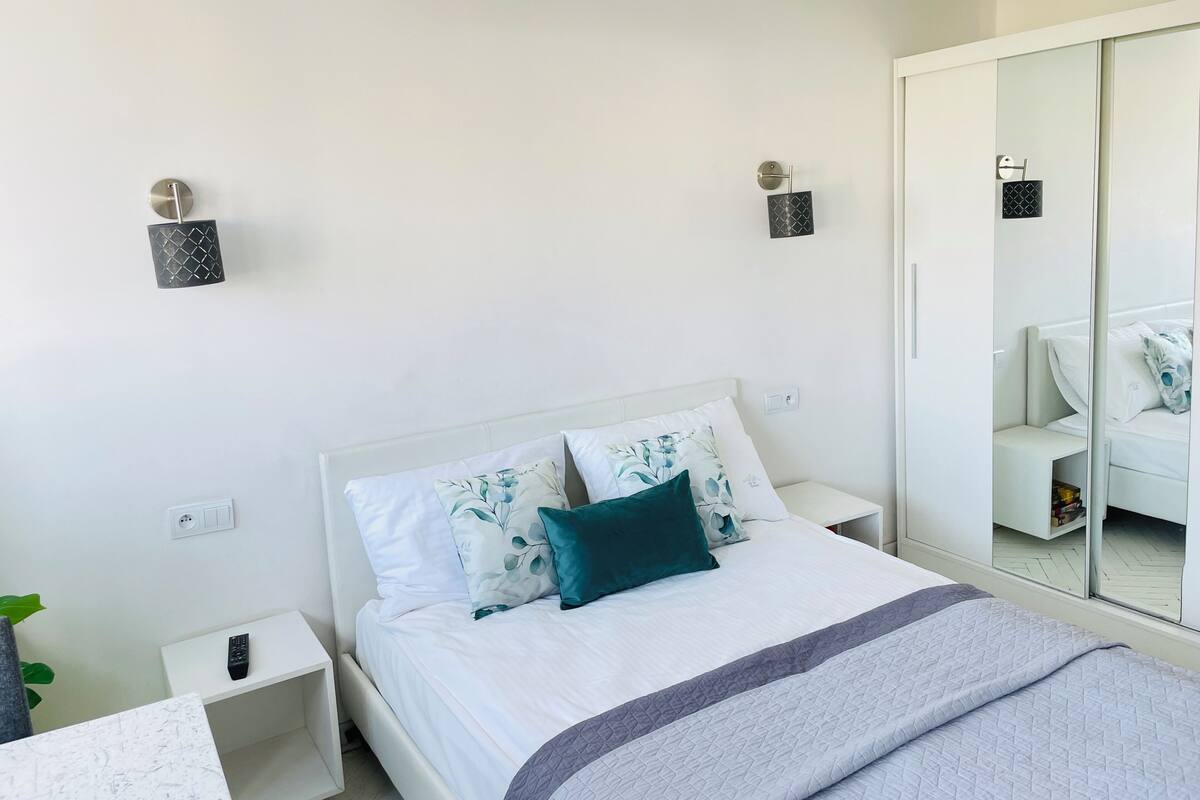 Una camera da letto moderna con un letto, comodini, uno specchio e un armadio.